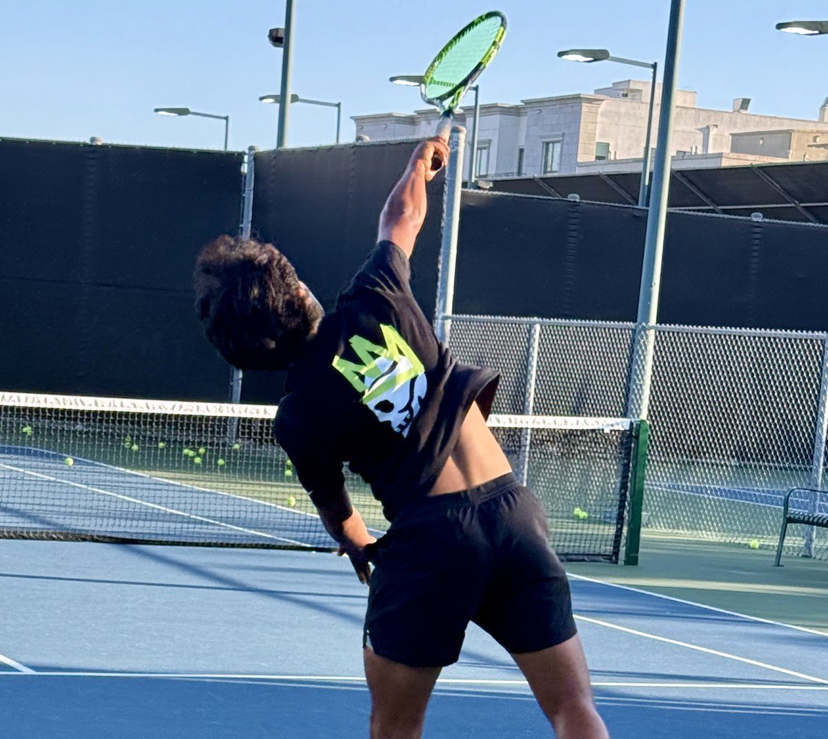 A junior player serving in a TNNS HEAD shirt
